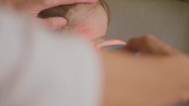 Ateşini ve profilini gösteren dijital kızılötesi termometreyle küçük hasta kızın ateşini ölçüyor. Çocuğun yüksek ateşi, salgını, grip salgını var. Yetişkin kızın ateşi kontrol ediliyor. Bebek iyileşiyor, soğuk.