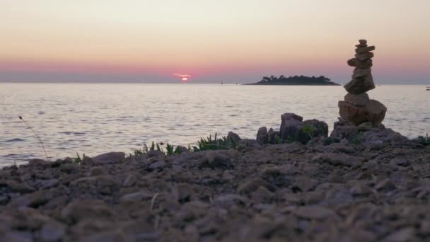 凯恩斯石滩上 青草映衬着粉红的大海 夕阳西下的天空和漆黑的岛屿 夕阳西下 石塔作为路标标志 浪漫的夏季探险 活跃在亚得里亚海度假 阳光下的石头 旅游目的地 假日概念 — 图库视频影像