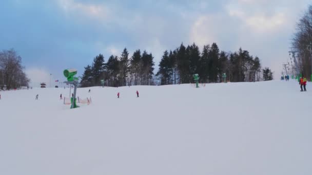 无法辨认的人在滑雪场滑雪场的T形杠升降时 手牵着手从斜坡上滑行 滑雪者在地面升降 冬季下山 爬山和滑雪家庭 冬季体育休假日 — 图库视频影像