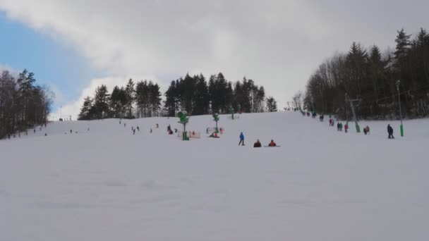 スキー場の斜面から雲と青空との戦いに身を委ねている認識できない人々 ハンドヘルド 雪の丘の上にスキーTバーの表面リフトを使用して 山を下るスキーヤー クライミングやスキーの家族 トレーニングコーチ 冬のアクティブなスポーツ休暇 — ストック動画
