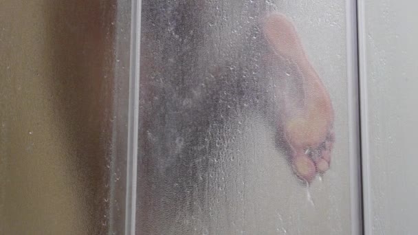 Un homme se baigne dans une douche, au ralenti, l'eau coule à travers le corps, mec humide, l'eau coule à travers le verre givré — Video