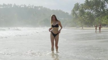 Srilanka plajında güzel bir kız mayo, okyanus ve uzun saçlarla yürüyor.