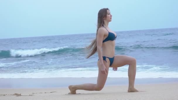 Ein schönes Mädchen im Bikini, trainiert, am Strand, am Indischen Ozean — Stockvideo