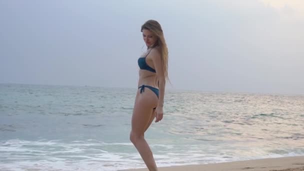 Beautiful, sporty women with long hair in bikini listens to music on earphones and dancing — Stock Video