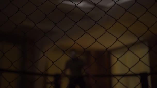 Ein Mann mit silberner Maske, hinter einem Gitter mit einem Messer in der Hand, geht — Stockvideo