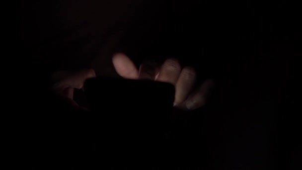 Hands in the dark, typing text messages on the phone — Stock Video