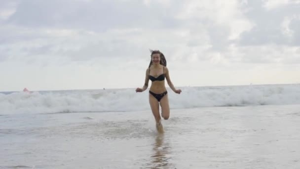 Νεαρό κορίτσι τρέχει έξω από το νερό, παραλία, συννεφιά καιρός, αργή κίνηση — Αρχείο Βίντεο