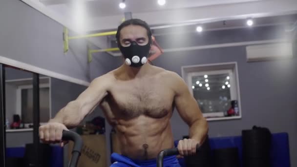 Un joven atleta, en una máscara de entrenamiento, entrena — Vídeos de Stock