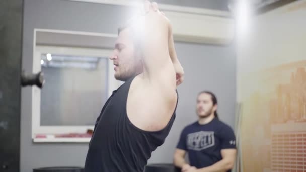 En man sträcker på musklerna, tränaren vaktar honom — Stockvideo