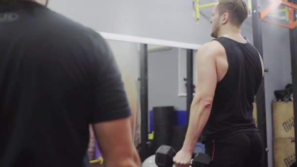 Hombre entrenadores bíceps con mancuernas, en el gimnasio, primer plano — Vídeo de stock