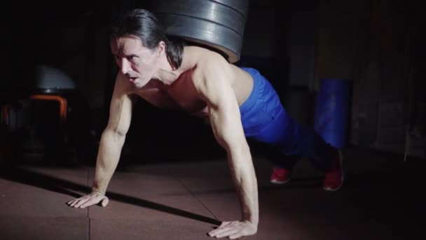Man with long hair does push-ups with weight — ストック動画