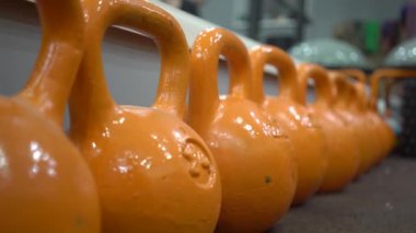 Spor salonunda turuncu ağırlıklar, omuzları çalıştıran adam.