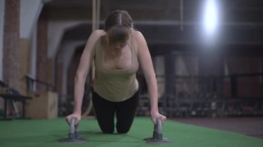 Güzel göğüslü spor kızı, şınav çeken, spor salonunda antrenman yapan.