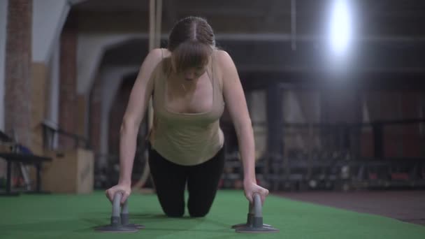 Sportmeisje met mooie borsten, doet push-ups, traint in de sportschool — Stockvideo