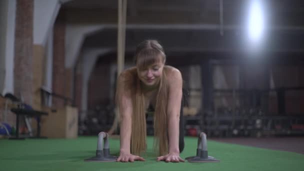 Vacker kvinna med långt blont hår, värmer upp, sträcker ut rygg och magmuskler, flörtar och skämtar — Stockvideo