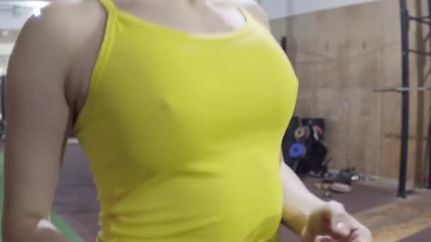 Mujer salta en una cuerda, en una camiseta amarilla, senos de mujer de cerca, cámara lenta — Vídeo de stock