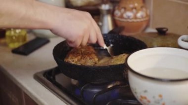 Bir adam, bir aşçı, mutfağındaki tavada et pişiriyor.