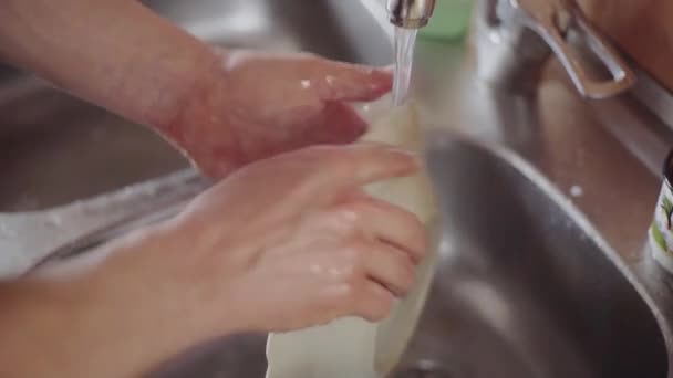 Um homem lava pratos na cozinha — Vídeo de Stock