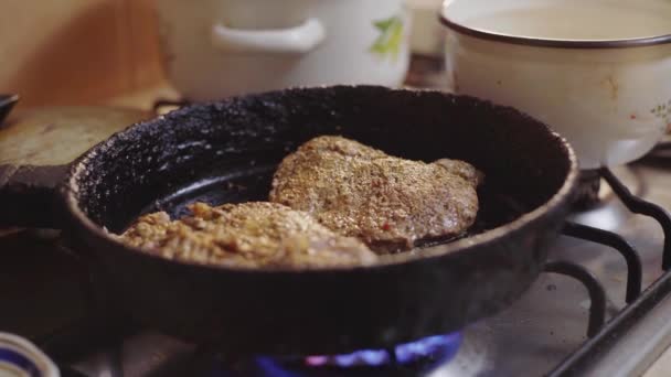 Um homem cozinha um bife em uma panela na cozinha, observa o cozimento de carne — Vídeo de Stock