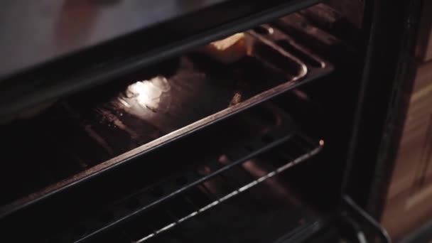 A man cooks in the kitchen, takes a cake out of the oven, checks it and hides it in the oven — Stock Video