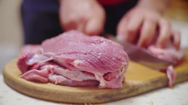 Un cuoco taglia carne cruda su un asse di legno, cucina una bistecca in cucina — Video Stock