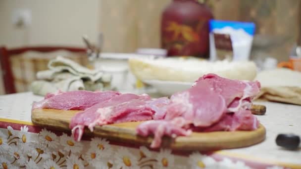 Man snijdt rauw vlees op een houten plank, kookt een steak in de keuken — Stockvideo