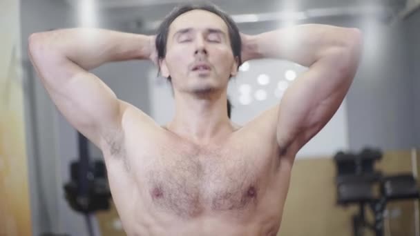 Athlète masculin, avec un torse nu, de beaux muscles, fait un échauffement, étire son cou — Video