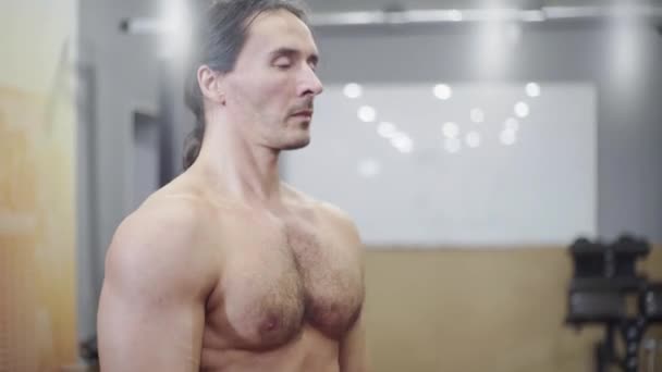 Homem adulto, um atleta, com um tronco nu, flexiona os ombros antes de treinar — Vídeo de Stock