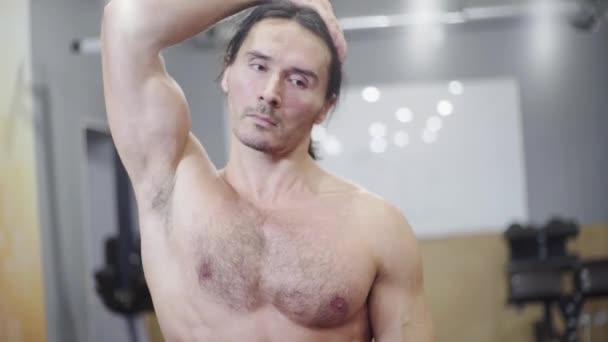 Guy atleet, met een mooie spieren, doet een warming-up, strekt zijn nek — Stockvideo