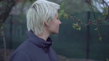 Sarışın, kısa saçlı bir kız, gece geç saatlerde bahçede yürür.