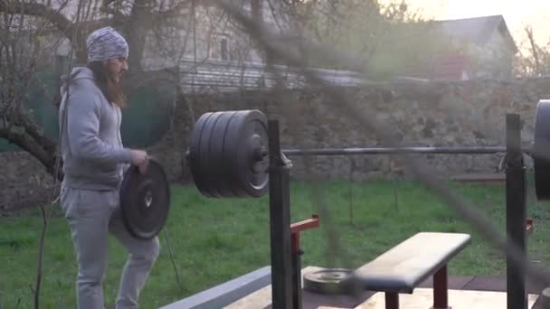 Un uomo, un atleta, all'inizio della primavera, si allena, prepara il bilanciere — Video Stock