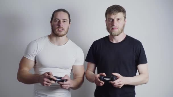 Two guys, gamers, play football intensely on a video game console, hold joysticks in their hands — Stock Video