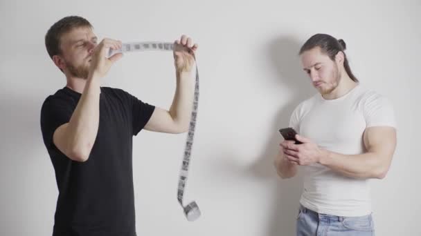 Zwei Männer stehen in einem hellen Raum, einer schaut sich den Film an — Stockvideo