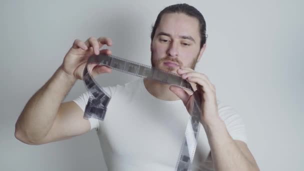 Homem atlético, fotógrafo, com barba vermelha examina o filme — Vídeo de Stock