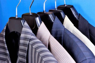 Mağazadaki askıda erkeklerin seçtiği ceketlerden. Bir adamın gardırobundaki ceket dekorasyon, aksesuar ve iş kıyafetleridir. Düğün, mezuniyet ve önemli bir etkinlik için sahneye koyun..