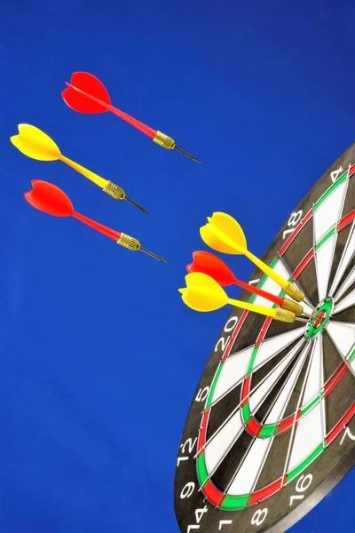 Target for sports Darts fly to the center, on a blue background. A game in which players rivals throw Darts and hit a round target to hit and win the tournament.