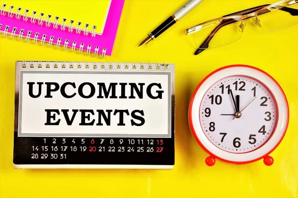 Upcoming events-text inscription on the calendar of business planning and education, clock symbol of time, remind of the past and future.