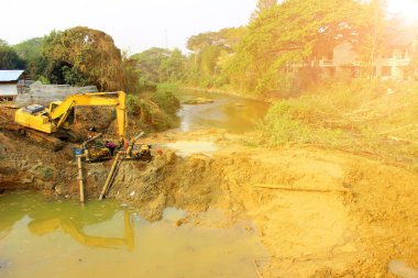 Bariyeri inşa etmek ve su bloklamak. Yaklaşan yağmur mevsiminde doğal afetlerden önce babadan akması gereken yol. Bir baraj inşa etmek.