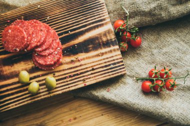 Gurme sağlıklı atıştırmalıklar dilimledi. Peynir ve sosis, zeytin, ahşap masadaki domatesler.
