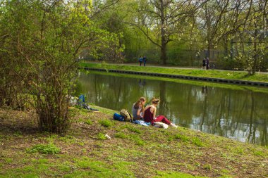 İnsanlar yerde oturuyor. Parkta dinlen. Piknik. Arkadaş toplantısı. Aile zamanı. Berlin 'in bir kısmı o gün Tiergarten' daydı. Berlin / Almanya - Mayıs 2019