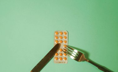 Çatal ve bıçakla hap iç. Beslenme konsepti. Tablet paleti. Kontrolsüz ilaç kullanımı. Uyuşturucu bağımlılığı. Yiyecek malzemeleri. Vitamin hapları. 