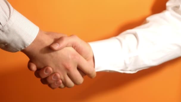 二人の男の友好的な握手 チームワークの概念 オレンジの背景 — ストック動画