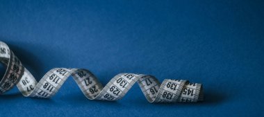 Klasik mavi arka planda şerit ölçüyorum. Terzilik konsepti. Diyet duvar kağıdı.