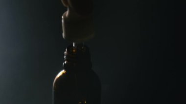 Kahverengi cam şişe. Şişeye yağ damlatıyor. Kozmetoloji ve sağlık konsepti.