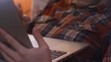 Yatakta yatan adamı kapat ve dizüstü bilgisayarı kullan. Ev konseptinde çalışmak. Bağımsız işler. İnternet kaydırılıyor