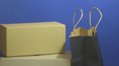 Para paketlerin üzerine düşüyor. İnternetten alışveriş konsepti. Klasik mavi arka planda karton kutular ve kese kağıdı. Bir yığın kağıt dolar. Kara Cuma. Reklam satışları. Boşluğu kopyala