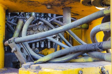 Kazıcının yanında motora bağlı birden fazla hortum ve kablo var..