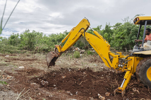 The operator of a bulldozer, with the backhoe is digging into the ground at a road construction site.