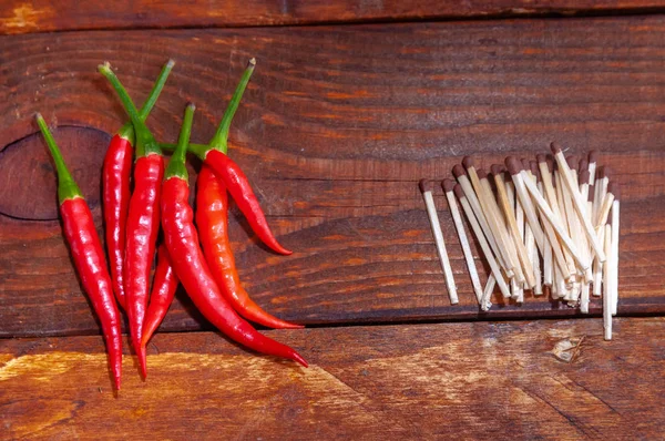 Red hot peppers lie opposite the match Stock Photo