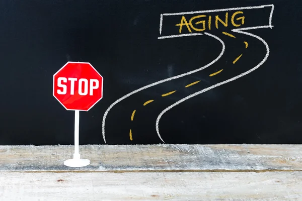 Mini STOP sign on the road to AGING — Stock Photo, Image